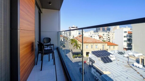 Un balcón con vista a un paisaje urbano, una silla y una mesa.
