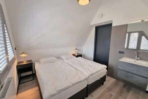 Ein Schlafzimmer mit einem Bett, Nachttischen, einem Spiegel und einem Fenster.