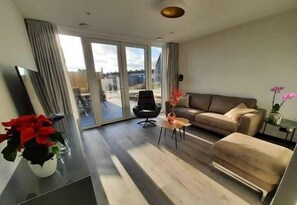 Ein modernes Wohnzimmer mit einer Couch, einem Couchtisch und einem Fernseher.