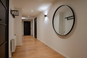 A hallway with wooden flooring, a round mirror on the wall, and a door at the end. - Spacious Apartment with Sauna & Roof Terrace in Domburg | Ooststraat 3 (Domburg)