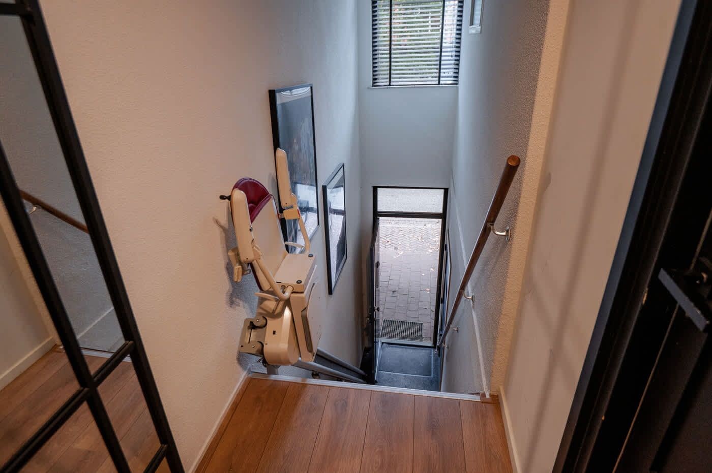 Eine Treppe mit Handlauf, einer Tür und einem Fenster mit Jalousien.