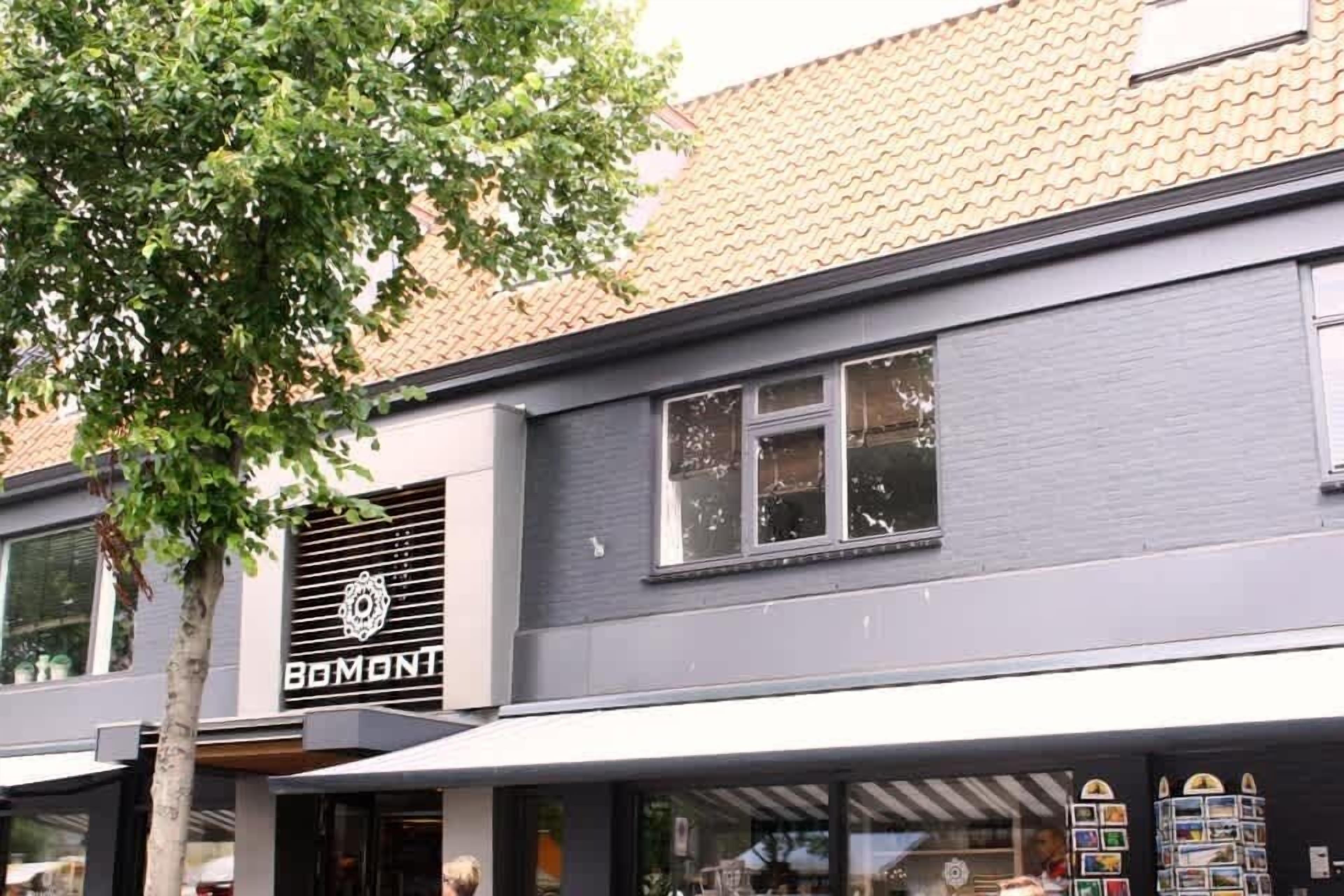 Ein Gebäude mit einer Fassade, auf der 'BOMONTI' steht, und ein Baum davor.