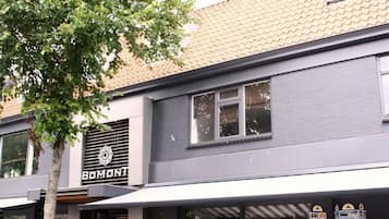 Ein Gebäude mit einer Fassade, auf der 'BOMONTI' steht, und ein Baum davor.