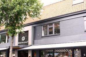 Ein Gebäude mit einer Fassade, auf der 'BOMONTI' steht, und ein Baum davor.