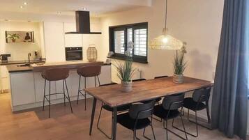 Eine moderne Küche mit Essbereich, ausgestattet mit einem Holztisch, schwarzen Stühlen und einer hängenden Leuchte.