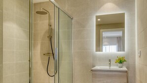A modern bathroom with a glass-enclosed shower, a wooden vanity, and a mirror above the sink. - Modern studio near marina - 2 guests (Estepona)