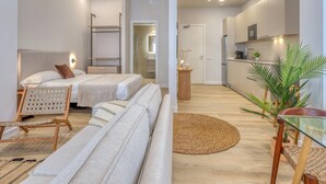 A modern hotel room with a bed, sofa, and a small kitchen area. - Modern studio near marina - 2 guests (Estepona)