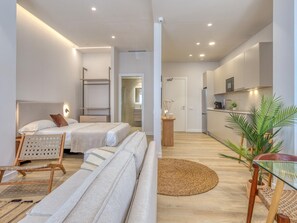 Ein modernes Hotelzimmer mit Bett, Sofa und einer kleinen Küchenzeile.