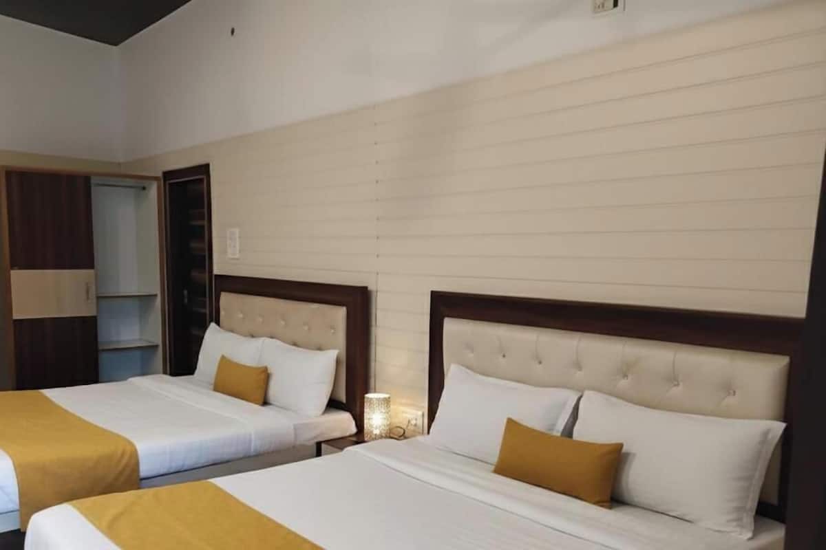 Una habitación de hotel con dos camas, un armario y una mesita de noche con lámpara.