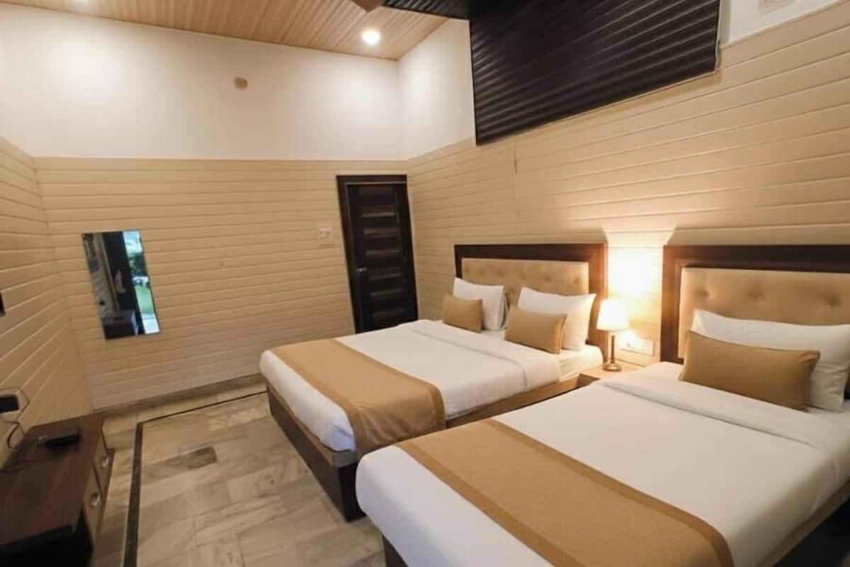 Habitación de hotel con dos camas, un espejo, una mesita de noche y una lámpara en el techo.