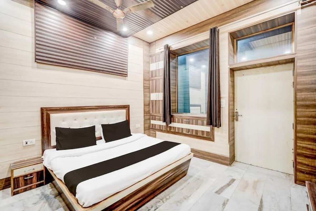 Un dormitorio con cama, ventilador de techo, ventana con cortinas y puerta.