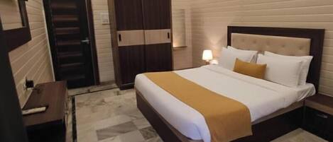A hotel room with a bed, bedside table, lamp, wardrobe, and a television.