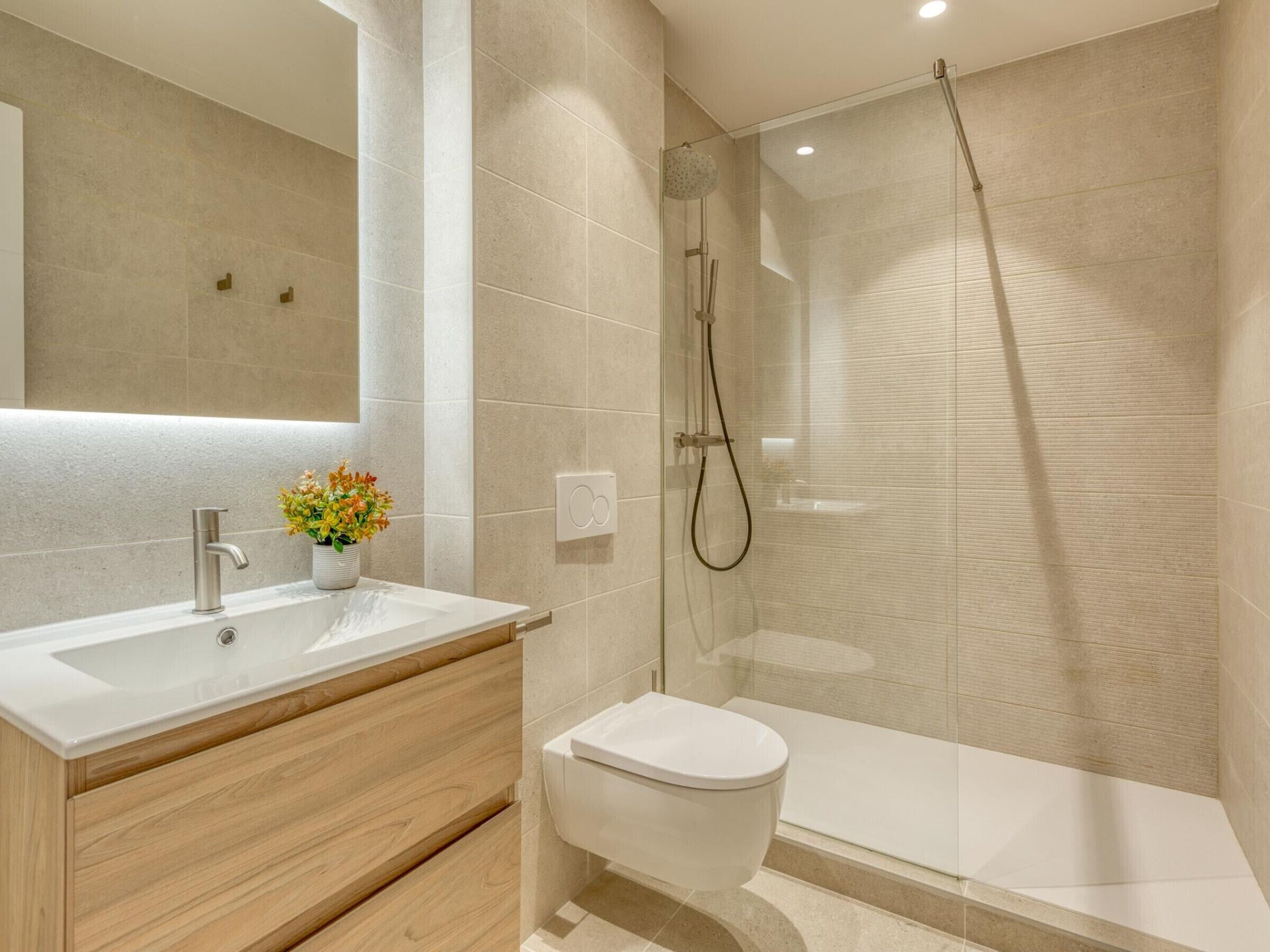 A modern bathroom with a shower, toilet, vanity, and a mirror.