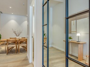 Ein modernes Interieur mit einem Holzesstisch, Stühlen, einem Spiegel und einer kleinen Pflanze auf einer Ablagetisch.