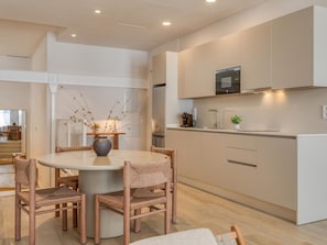 A modern kitchen with a round dining table, wicker chairs, and a vase with dried branches. - Modern studio near the port - ? guests (Estepona)