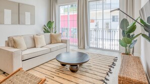 Un saló modern amb un sofà, una taula de centre rodona i una finestra gran amb cortines.