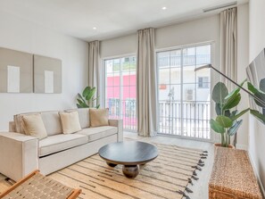 A modern living room with a sofa, a round coffee table, and a large window with curtains. - Modern studio near the port - ? guests (Estepona)