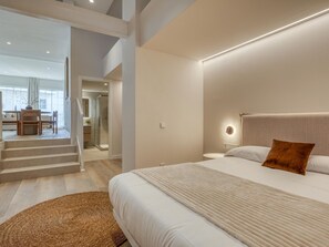 A modern bedroom with a large bed, a bedside table, and a nightstand. There is a staircase leading to an upper level. - Modern studio near the port - ? guests (Estepona)