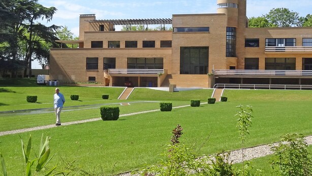 Un bâtiment moderne doté d’un toit plat, de nombreuses fenêtres et d’un escalier central.