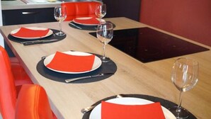 Une table à manger est dressée avec des serviettes rouges, des assiettes et des verres à vin, et on peut apercevoir une chaise rouge.