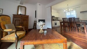 A dining area with a wooden table and chairs, a mirror on the wall, and a kitchen in the background. - Spacious house with garage - 6 guests (Banyuls-sur-Mer)