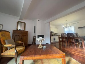 A dining area with a wooden table and chairs, a mirror on the wall, and a kitchen in the background. - Spacious house with garage - 6 guests (Banyuls-sur-Mer)