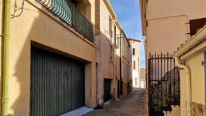 A narrow stone-paved alleyway between buildings with a closed green shutter door and a metal gate. - Spacious house with garage - 6 guests (Banyuls-sur-Mer)