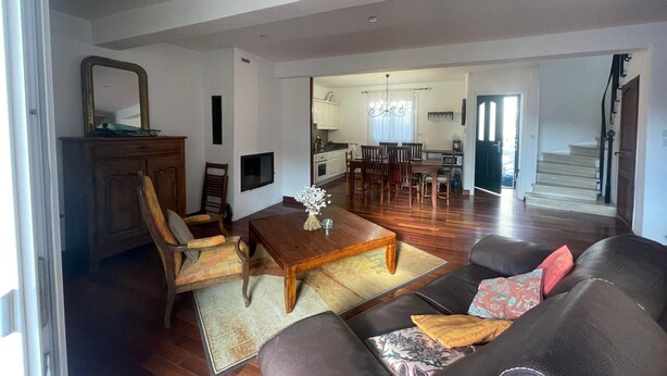A spacious living area with a sofa, chairs, a coffee table, and a dining table. There is a kitchen in the background with cabinets and a chandelier. - Spacious house with garage - 6 guests (Banyuls-sur-Mer)