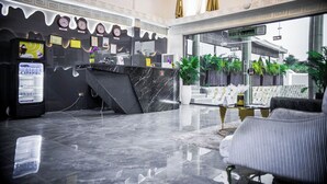 A modern hotel lobby with a reception desk, a refrigerator, and a seating area.