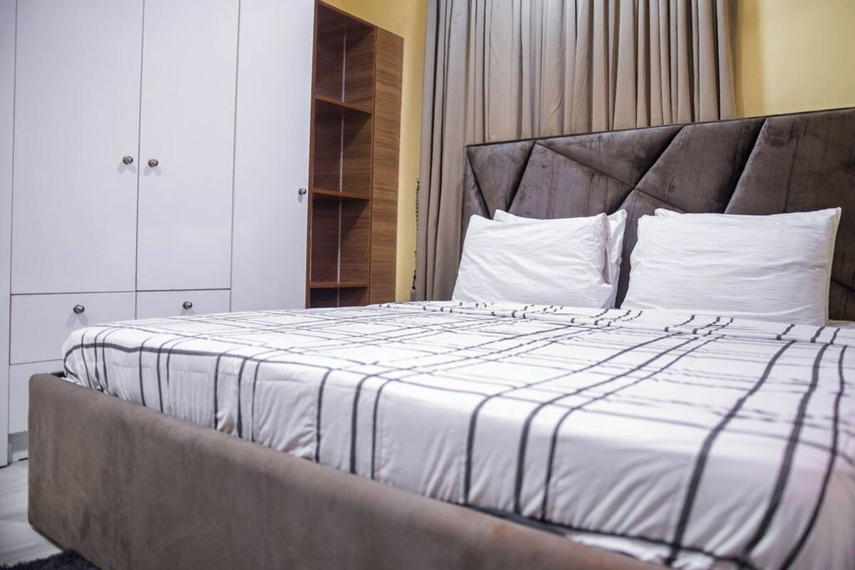 A bedroom with a bed, a wardrobe, and a built-in shelving unit.