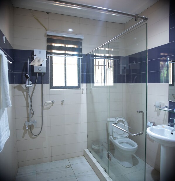 A bathroom with a glass-enclosed shower, a toilet, and a sink.