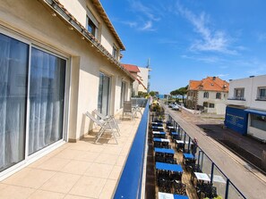 Ein Balkon mit Sitzgelegenheit, Blick auf die Straße und ein Gebäude mit rotem Dach.