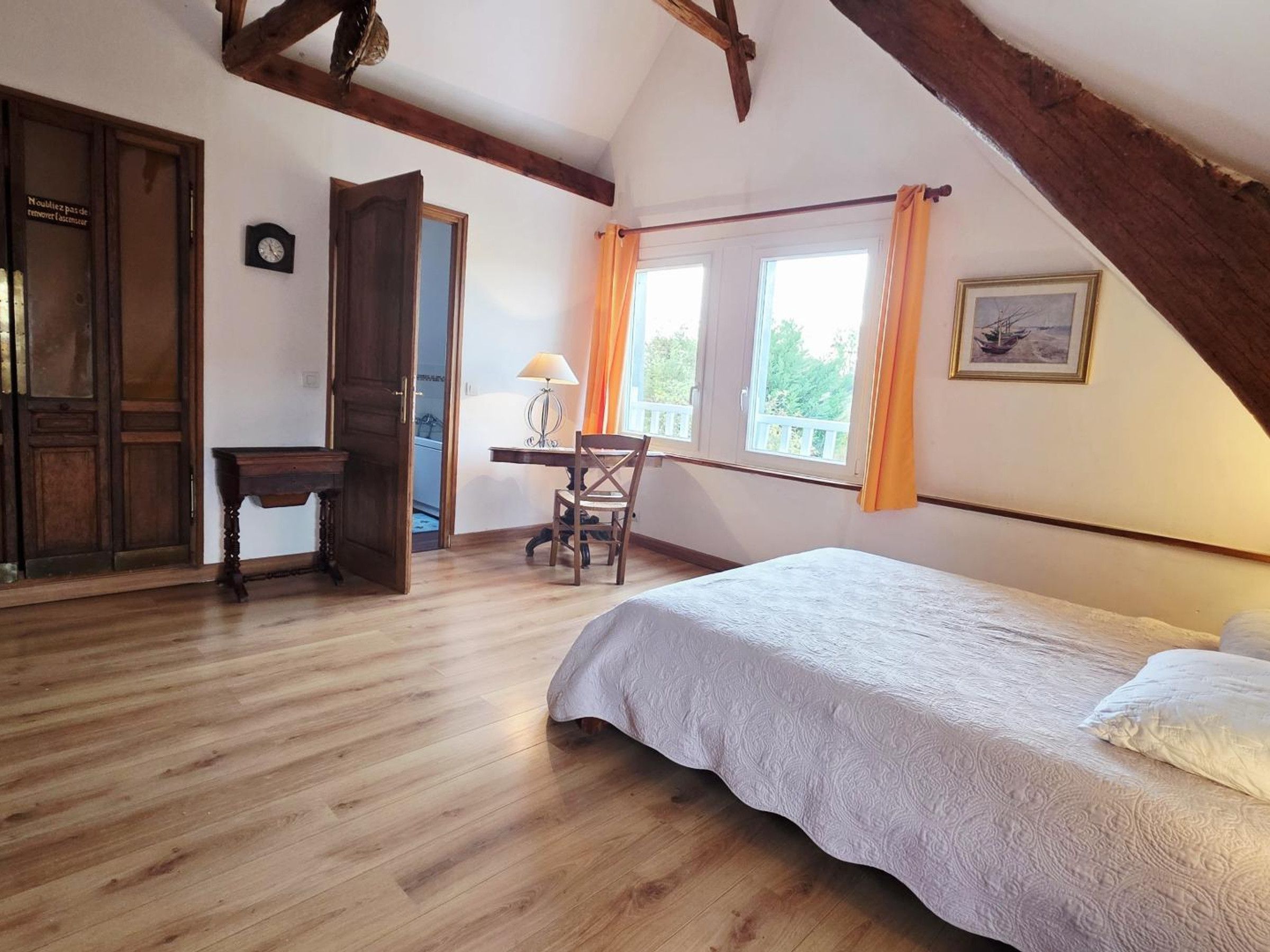 Une chambre avec un lit, un bureau et une chaise. Il y a une fenêtre avec des rideaux, une porte et une horloge au mur.
