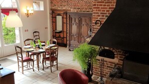 Un coin repas avec un mur en briques, une cheminée et une table dressée pour deux personnes.