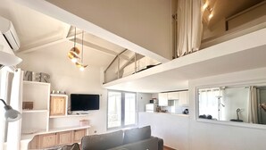 A modern apartment with a dining area, kitchen, and living room. - Mezzanine studio, air con, parking - canal view (Sète)