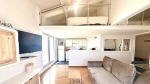 A modern loft-style apartment with a living area, kitchen, and a mezzanine bedroom. - Mezzanine studio, air con, parking - canal view (Sète)