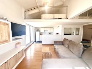 Eine moderne Loft-Wohnung mit Wohnbereich, Küche und einem Schlafzimmer im Zwischengeschoss.