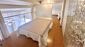 A bedroom with a bed, a balcony, and a decorative wall. - Mezzanine studio, air con, parking - canal view (Sète)