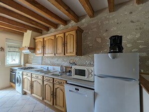 Une cuisine équipée de meubles en bois, d’une cuisinière, d’un four à micro-ondes, d’un lave-vaisselle et d’un réfrigérateur.