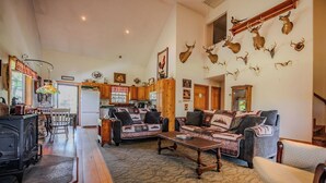 A cozy living room with a fireplace, a dining area, and a kitchen. - Glatts - Cabin located in Shunk (Shunk)