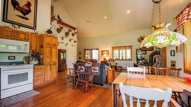 A spacious kitchen with wooden cabinets, a dining table, and a chandelier. - Glatts - Cabin located in Shunk (Shunk)