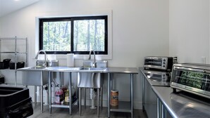 A modern kitchen with stainless steel appliances, a large window, and a view of trees.