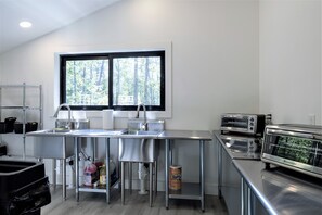 A modern kitchen with stainless steel appliances, a large window, and a view of trees.