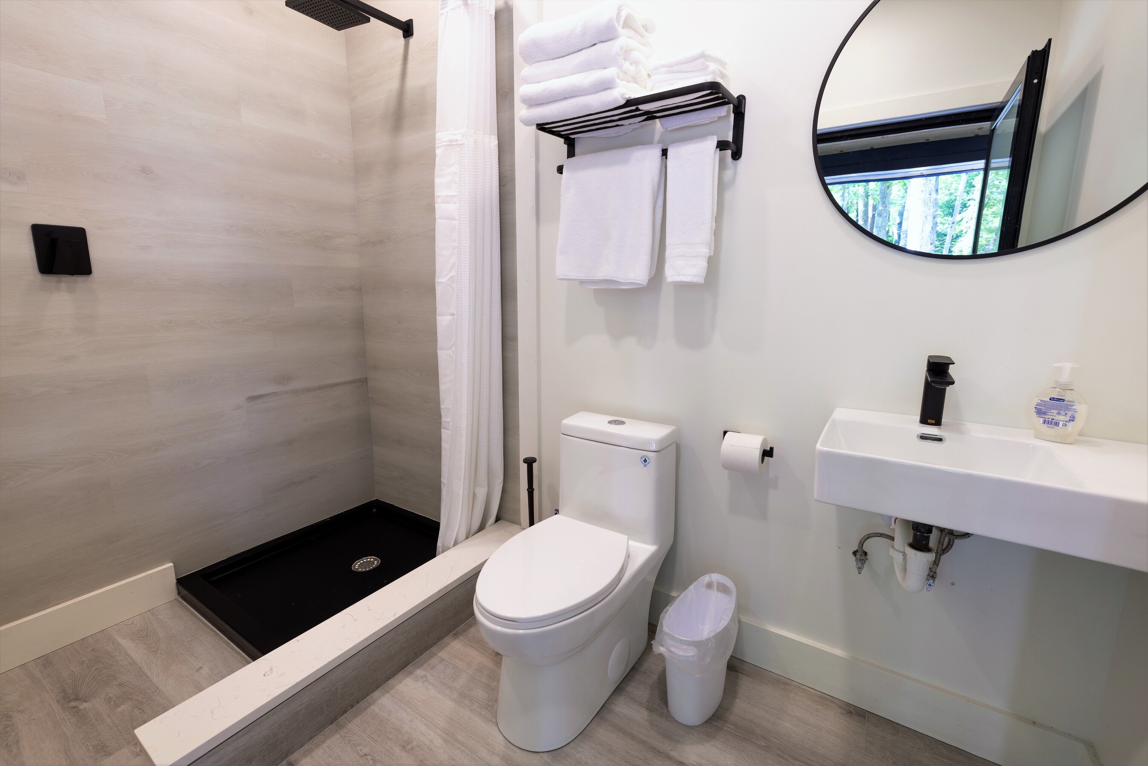 A modern bathroom with a shower, toilet, and sink.