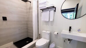 Een moderne badkamer met douche, toilet en wastafel.