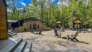 A cabin with a stone exterior, a covered outdoor seating area, and two glass-roofed structures.