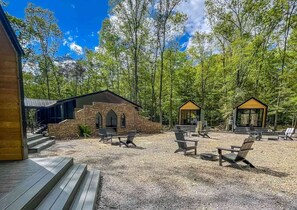 A cabin with a stone exterior, a covered outdoor seating area, and two glass-roofed structures.
