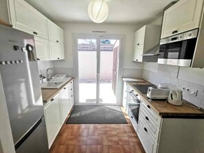 Eine Küche mit weißen Schränken, einem Edelstahl-Kühlschrank, einer Mikrowelle und einem Herd.