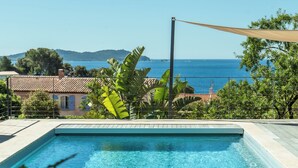 Una piscina con vistas al mar y colinas al fondo.