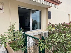 Ein Gebäude mit einem großen Fenster, einem grünen Metallzaun und Topfpflanzen.